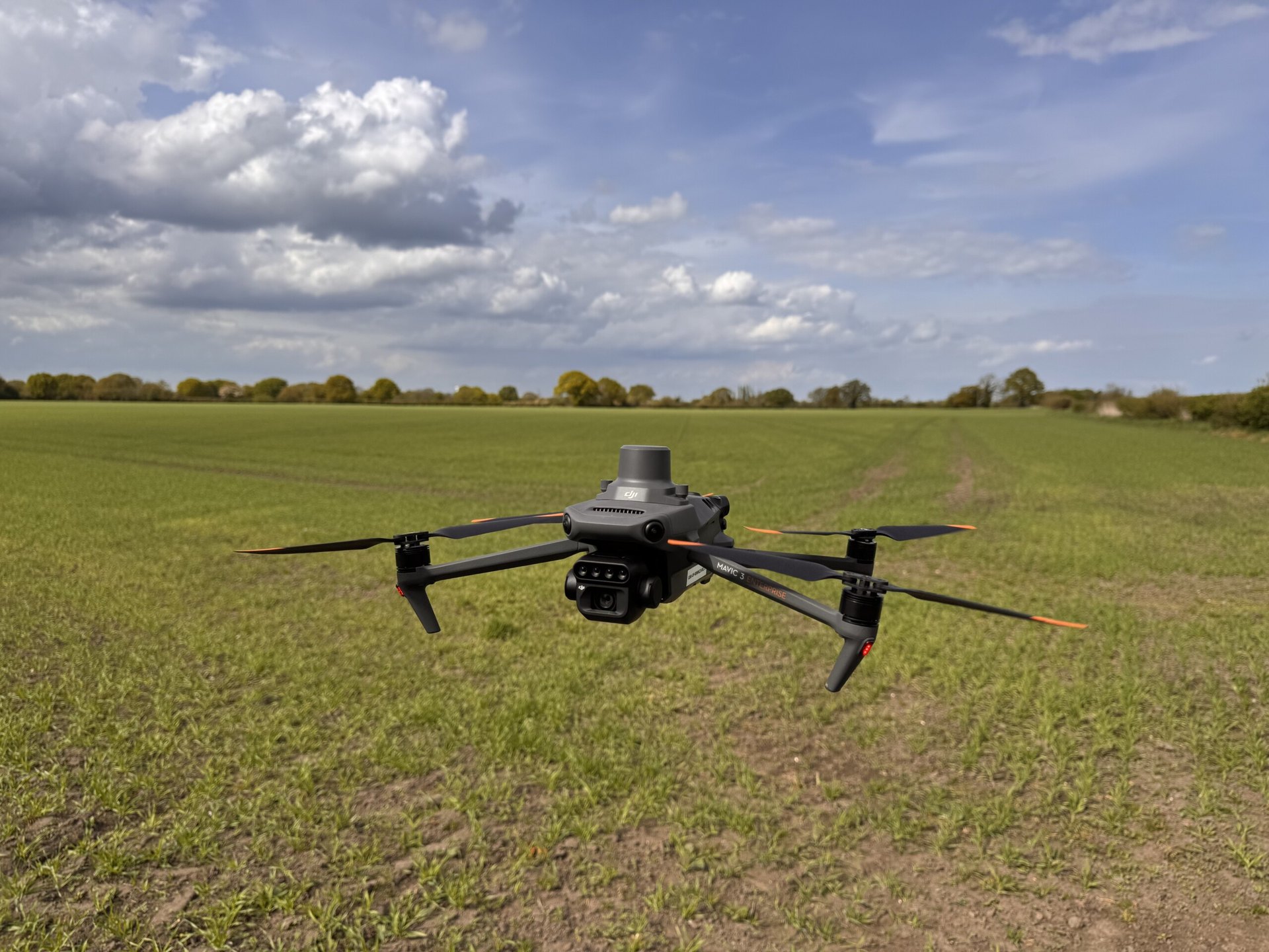 DJI Mavic 3M multispectral drone flying low over a crop