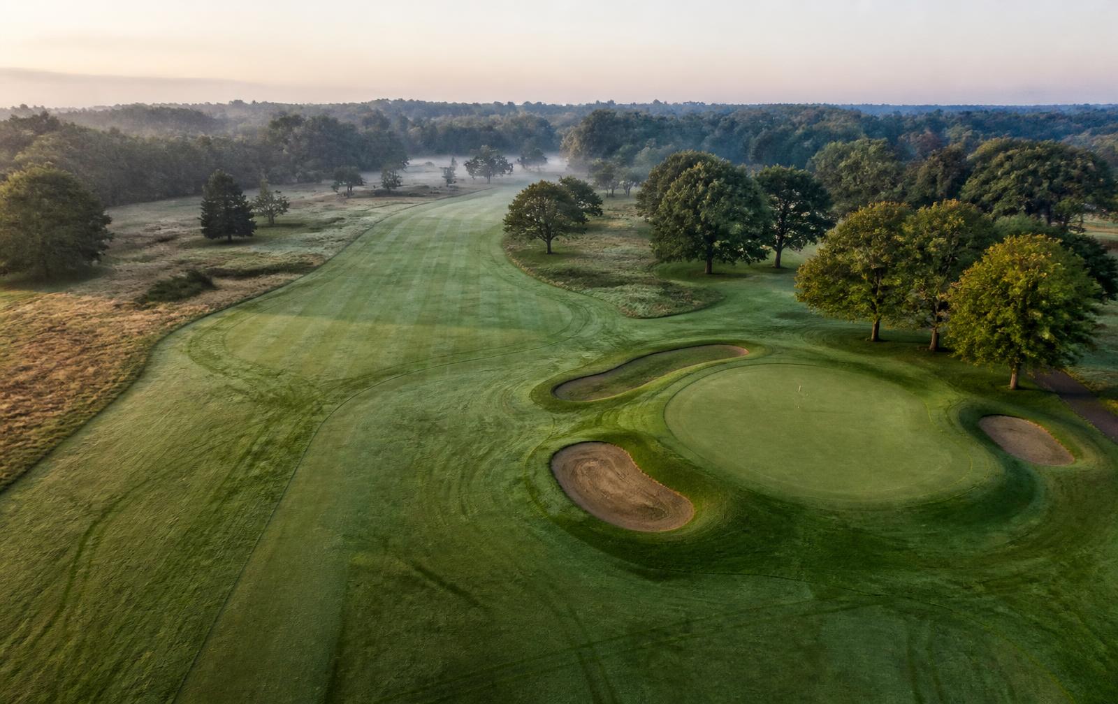 Aerial view of a golf course fairway, green and bunkers at first light